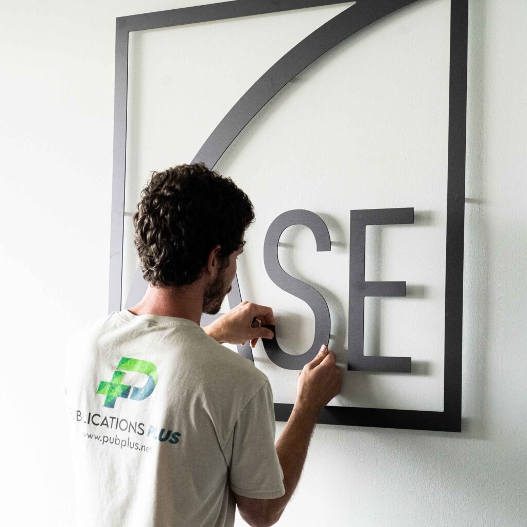 A man is installing a black minimalist indoor sign.