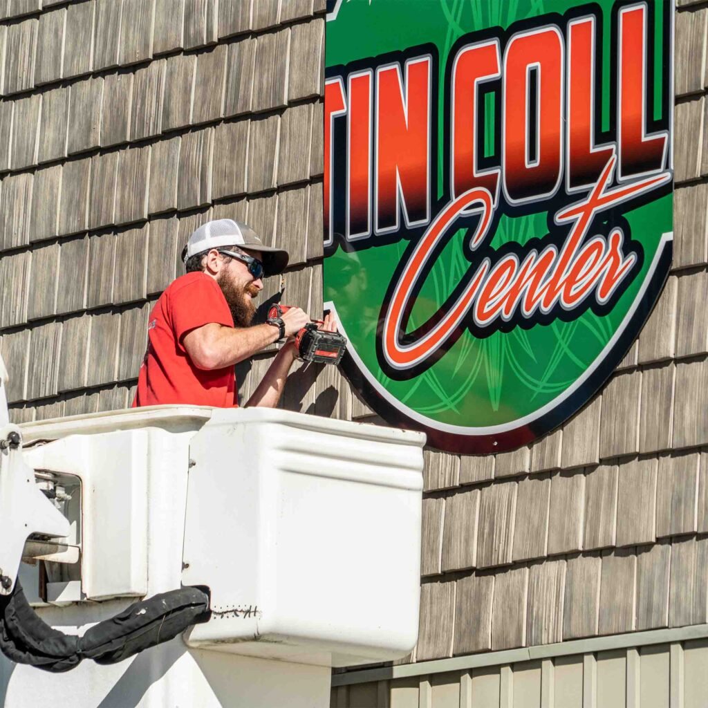 Man in bucket truck drilling into outdoor sign.