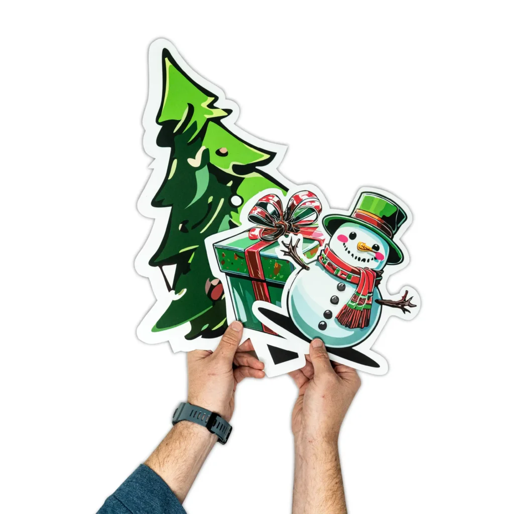 Hands holding Christmas themed sample prints of window clings.